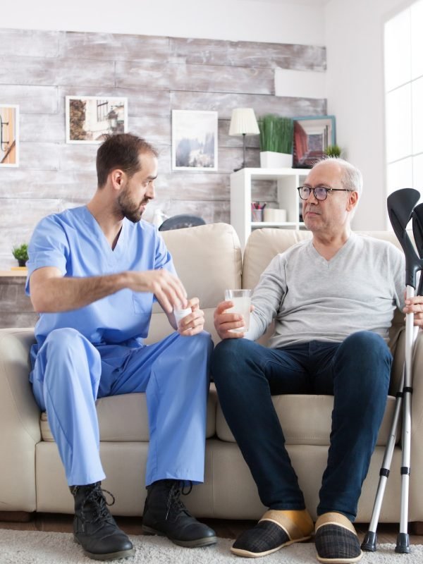 young-male-nurse-in-nursing-home-with-pills-for-senior-man.jpg